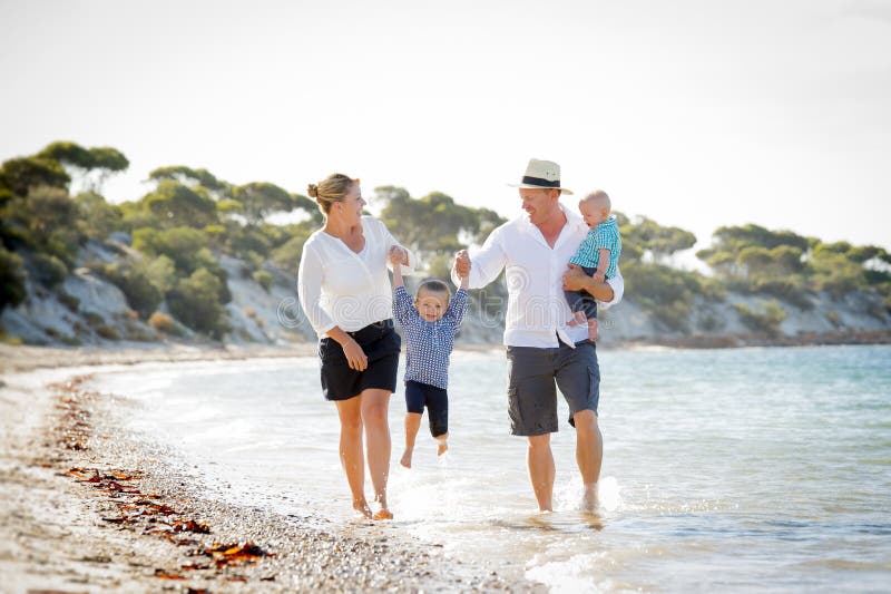 Young happy beautiful family walking together on the beach enjoying summer holidays royalty free stock photo Young happy beautiful family walking together on the beach enjoying summer holidays royalty free stock photo
