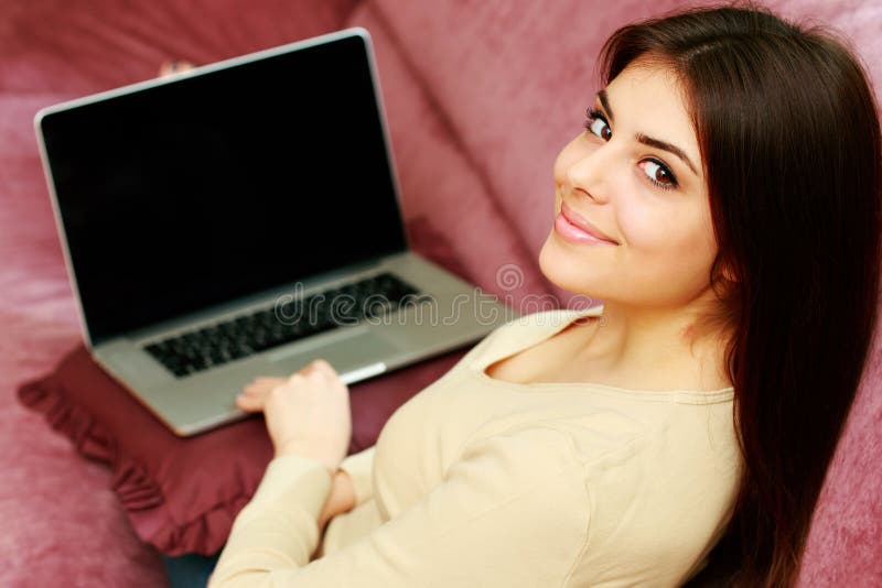 Young happy beautiful woman sitting on the sofa with laptop