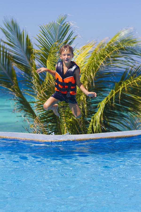 Young happy boy jumping in swimming pool