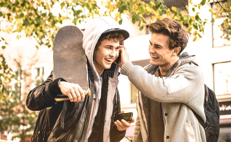 Young happy brothers having fun using mobile smart phones stock photo Young happy brothers having fun using mobile smart phones stock photo