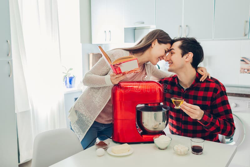 Young happy couple cooking on kitchen with food processor. Woman and man reading recipe and hugging stock photos Young happy couple cooking on kitchen with food processor. Woman and man reading recipe and hugging stock photos
