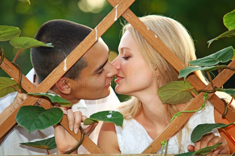 Young happy couple kissing at wooden lattice