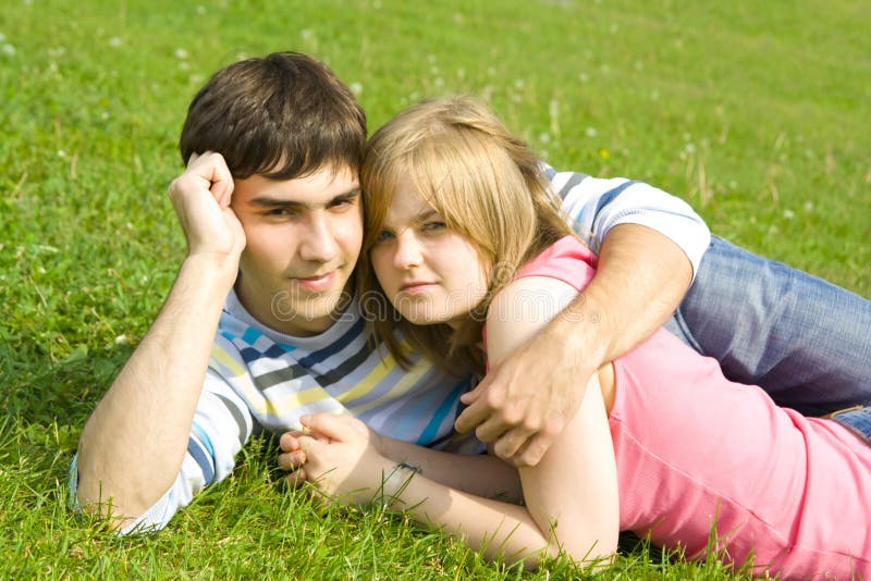 Young happy couple laying on a green grass