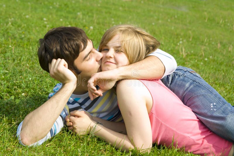 Young happy couple laying on a green grass