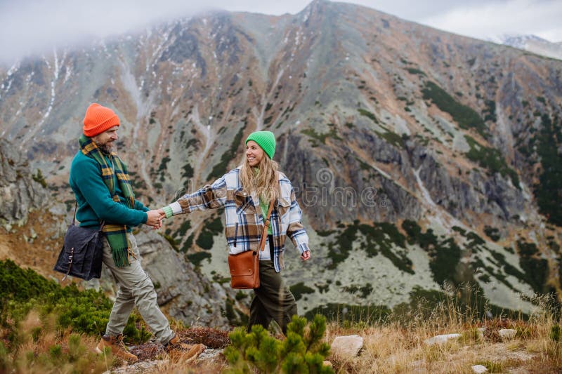 Young happy couple at mountain hike, holding hands.