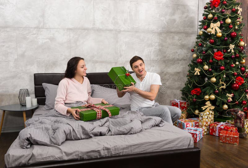Young happy couple in pajamas rejoice at their presents while si stock images Young happy couple in pajamas rejoice at their presents while si stock images