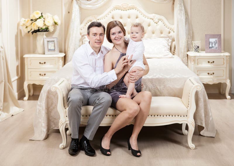 Young happy family with a baby on bed stock photo Young happy family with a baby on bed stock photo