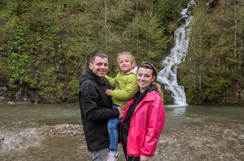 Young happy family: mom, dad and daughter on the background of a mountain waterfall royalty free stock photos Young happy family: mom, dad and daughter on the background of a mountain waterfall royalty free stock photos