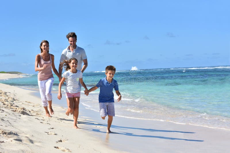 Young happy family running on the beach having fun