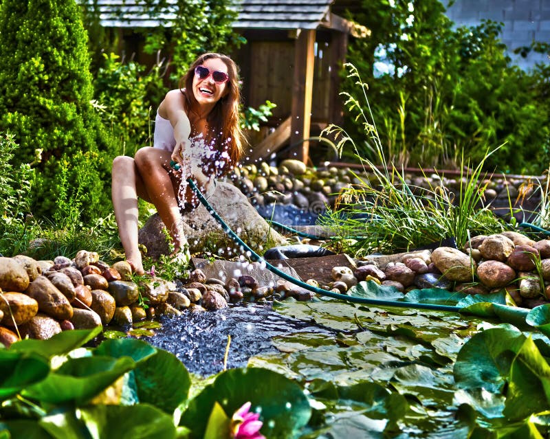 Young happy girl with garden streamlet near pond