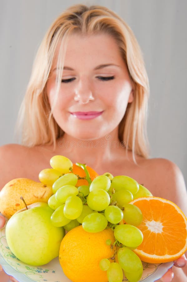 Young happy girl with a plate of juicy fruits