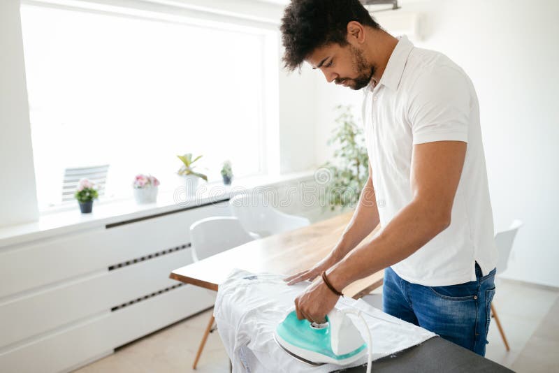Young Happy Man Ironing Clothes.