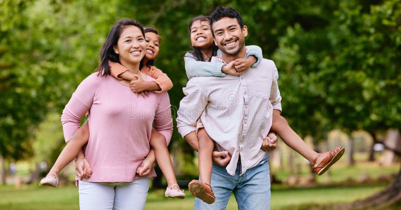 Young happy mixed race family relaxing and walking together in a park. Loving hispanic parents giving their daughters a