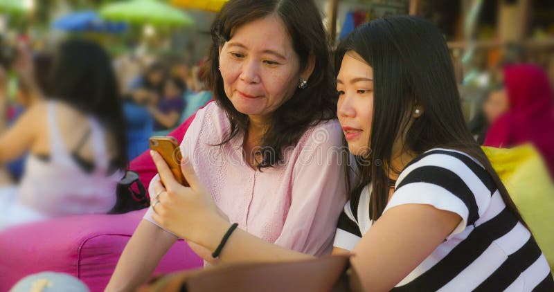 Young happy and pretty Asian Chinese girl on the beach taking selfie photo with her mother, a 60s mature woman , enjoying Summer royalty free stock photography Young happy and pretty Asian Chinese girl on the beach taking selfie photo with her mother, a 60s mature woman , enjoying Summer royalty free stock photography