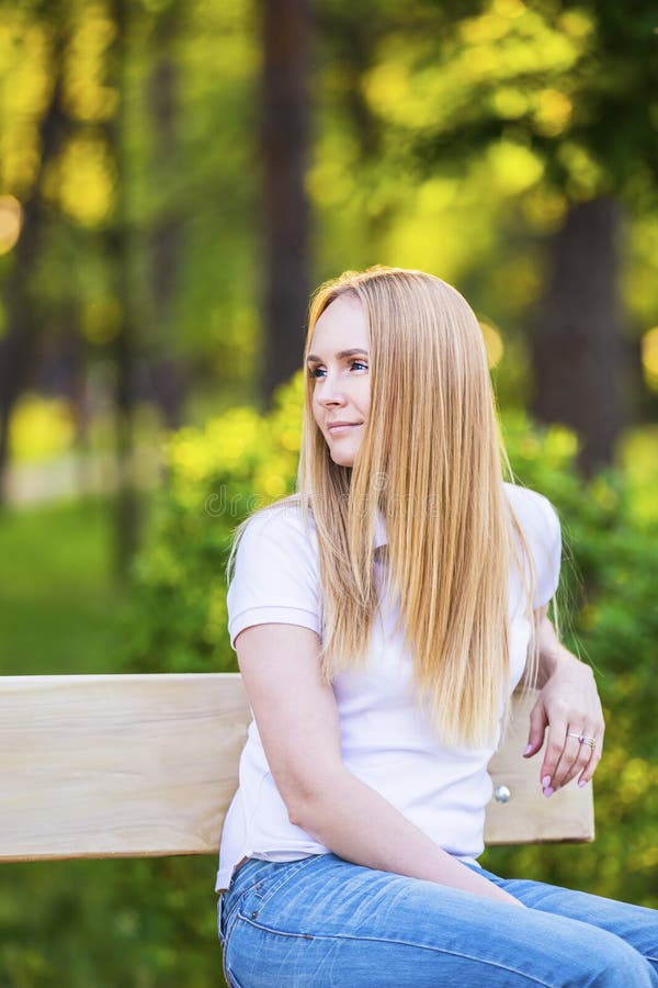 Young, happy, thin young blond woman with long beautiful hair, smiling, in the summer park under the rays of the sun royalty free stock images Young, happy, thin young blond woman with long beautiful hair, smiling, in the summer park under the rays of the sun royalty free stock images