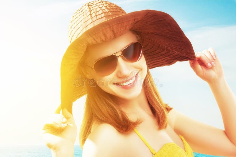 Gesicht einer Jungen glücklich Frau am Strand im bikini, eine Sonnenbrille und einen Hut.