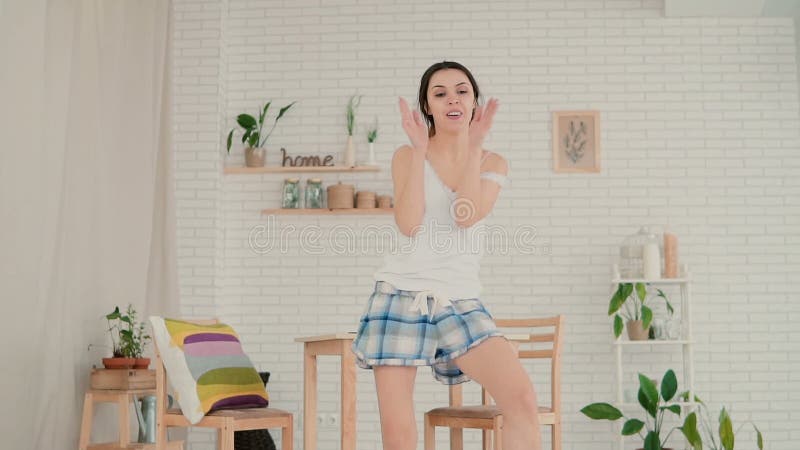 Young happy woman in pajamas dancing at home. Attractive girl haves fun in the kitchen. Slow motion.