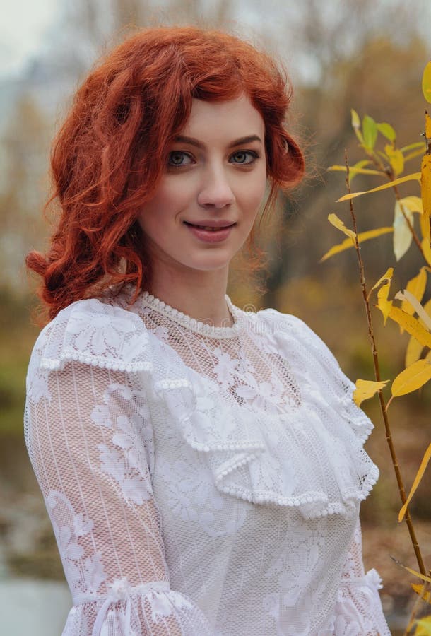 Young happy woman in a park near the river in autumn season