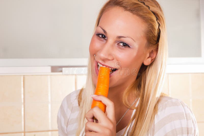 Young healthy woman eating fresh carrots