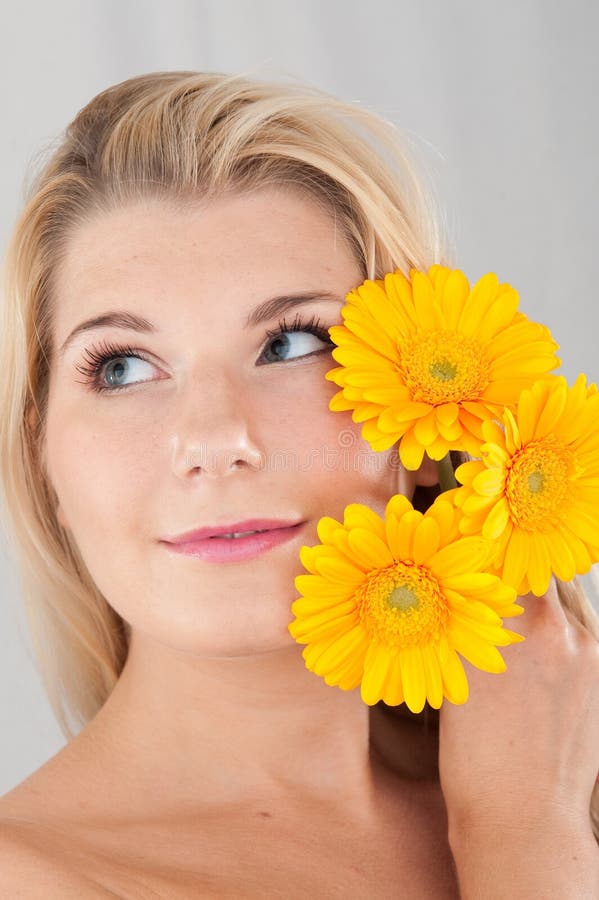 Young healthy woman with three yellow flowers