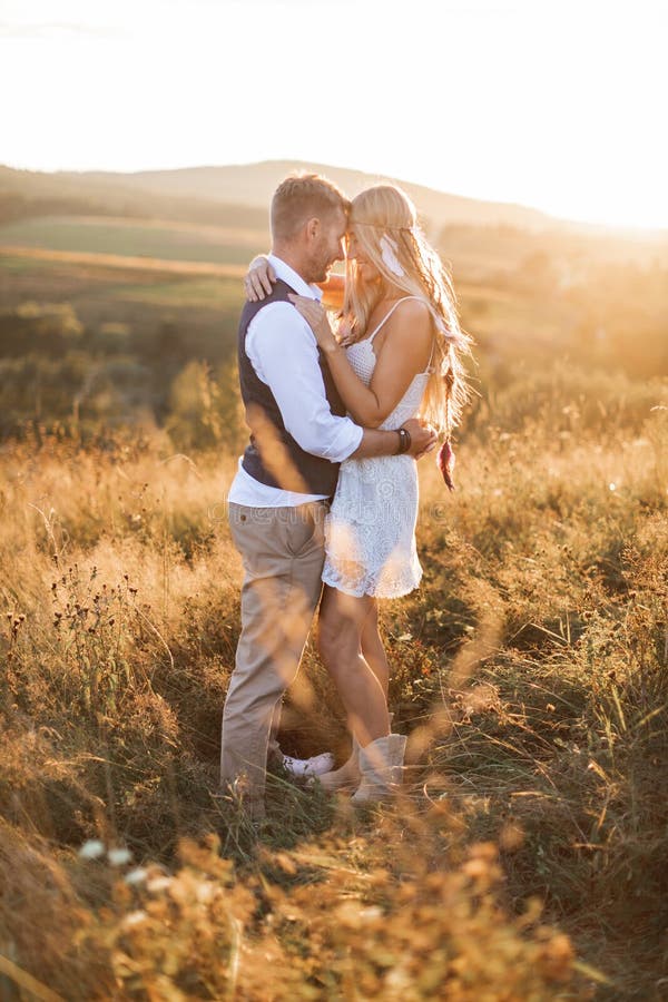 Young hippie boho couple in love outdoors. Portrait of young stylish fashion couple posing in summer in field, hugging