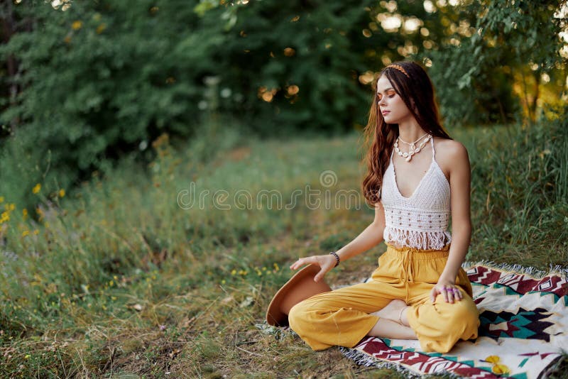 A Young Hippie Woman Meditates in Nature in the Park, Sitting in a ...