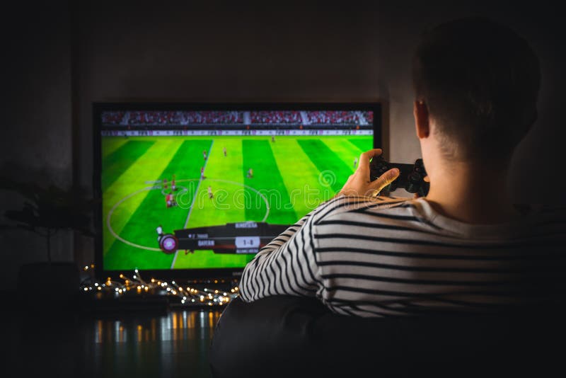 Young hipster man playing video game football soccer on console. gamer guy with gamepad controller holding Wireless joystick sitti