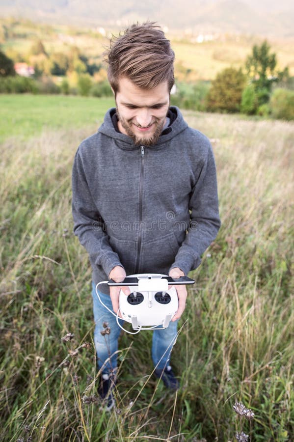 Young hipster man with remote control. Sunny green nature. royalty free stock images