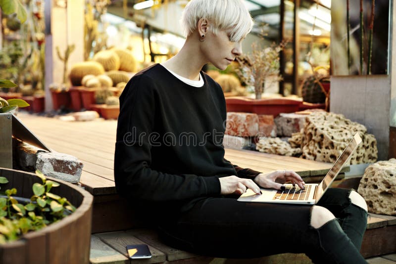 Young hipster woman with blonde short hair sitting on stairs, working on laptop stock photos Young hipster woman with blonde short hair sitting on stairs, working on laptop stock photos