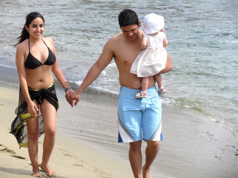 Young hispanic family walking on the beach