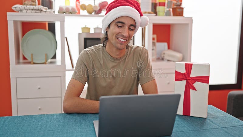 Mladý hispánsky muž s volanie držanie vianočný darček na jedálenský.