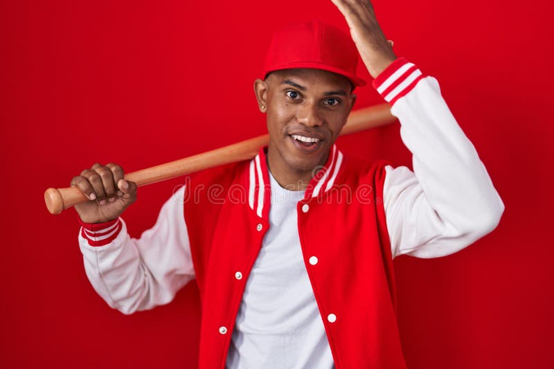 Young Hispanic Man Playing Baseball Holding Bat Surprised with Hand on