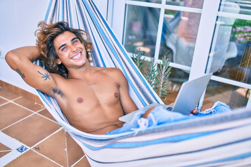 Young hispanic man relaxed working using laptop lying on the hammock at terrace stock photography