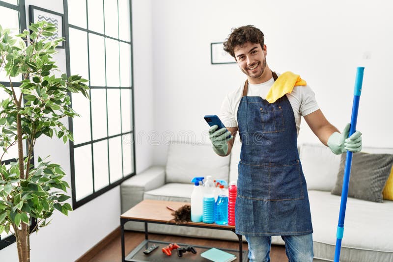 Young hispanic man smiling confident cleaning and using smartphone at home royalty free stock photos
