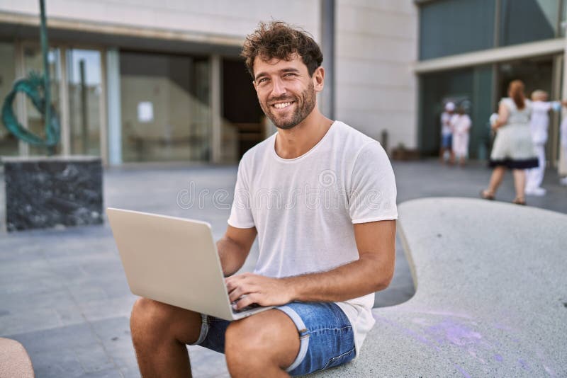Young hispanic man smiling confident using laptop at street royalty free stock photography