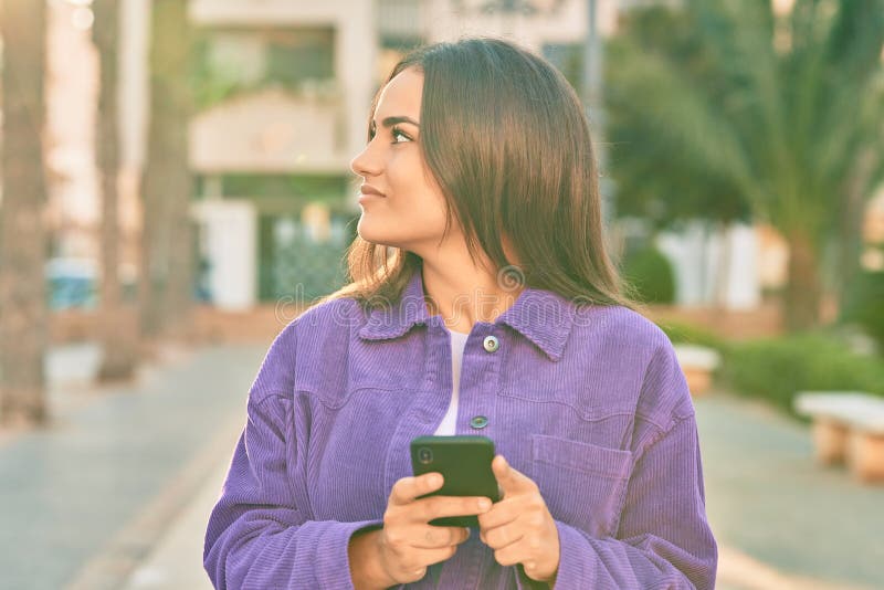 Young hispanic woman smiling happy using smartphone at the city stock photo