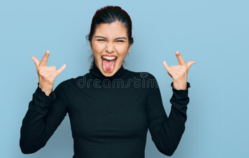 Young hispanic woman wearing casual clothes shouting with crazy expression doing rock symbol with hands up