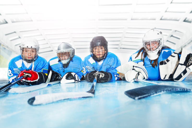 Young hockey players laying on ice rink in line.