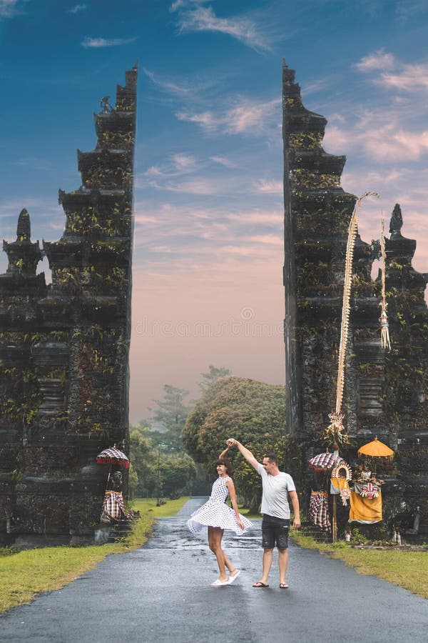 Young honeymoon couple on a big balinese gates background. Bali island, Indonesia.