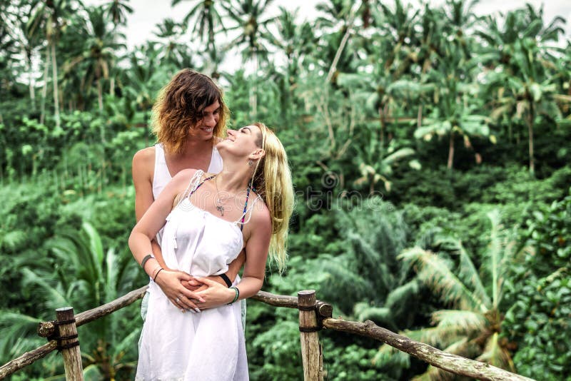 Young honeymoon couple posing on the bridge deep in the jungle. Rainforest of Bali island. Romantic shoot. Indonesia.