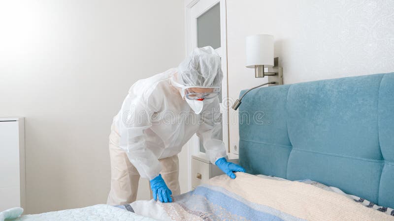 young housewife protective biohazard suit making up bed covid pandemic lockdown 206845377