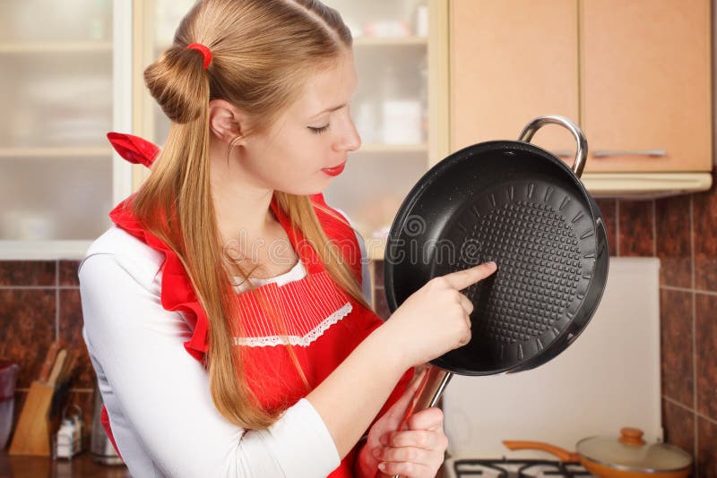Cooking utensils. Cooking woman in kitchen with frying pan and wooden  spoon. Housewife dancing. Stock Photo