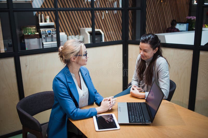 Young HR woman interviews a candidate for a job. Business meeting two young women at work discussing the project