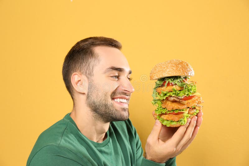 Young hungry man eating huge burger