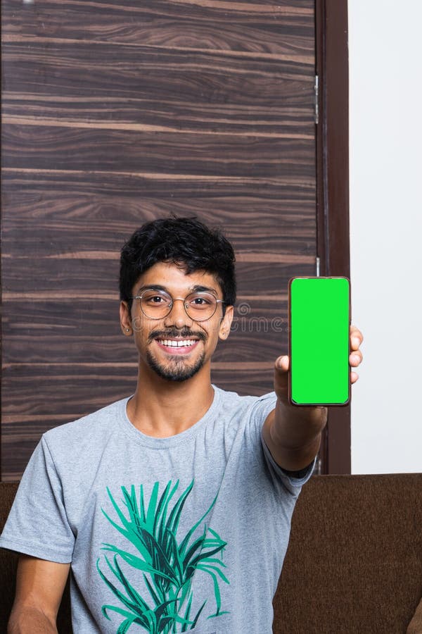 Young Indian Boy Holding a Mobile Phone with a Green Screen on it Stock ...