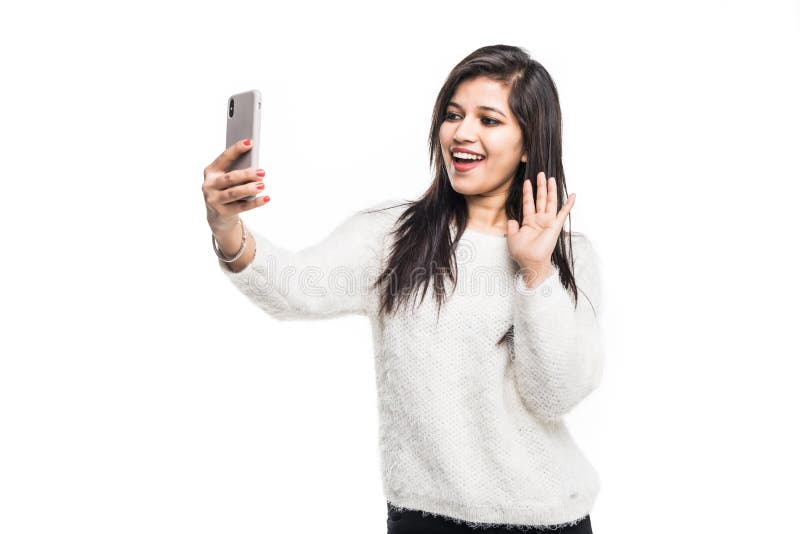 Young Indian girl using a mobile phone or smartphone, talking selfie or talking on video chat isolated on a white background