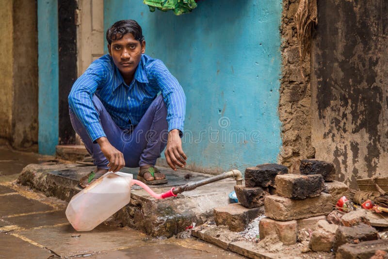 Young Indian man filling water bottle