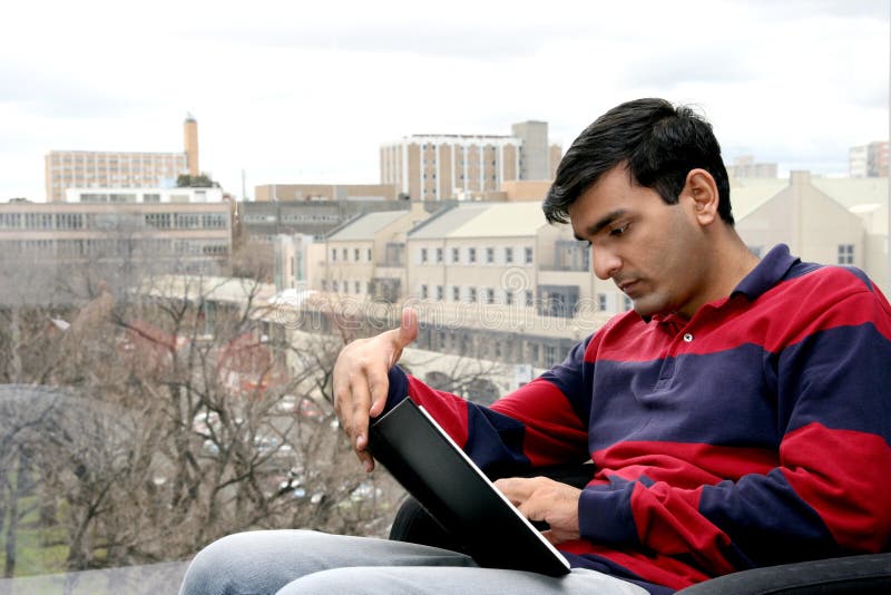 Mladý indický študent pracovné na jeho prenosný počítač v univerzita.