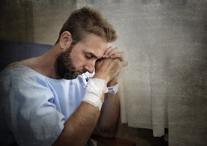 Young injured man in hospital room sitting alone in pain worried for his health condition royalty free stock image