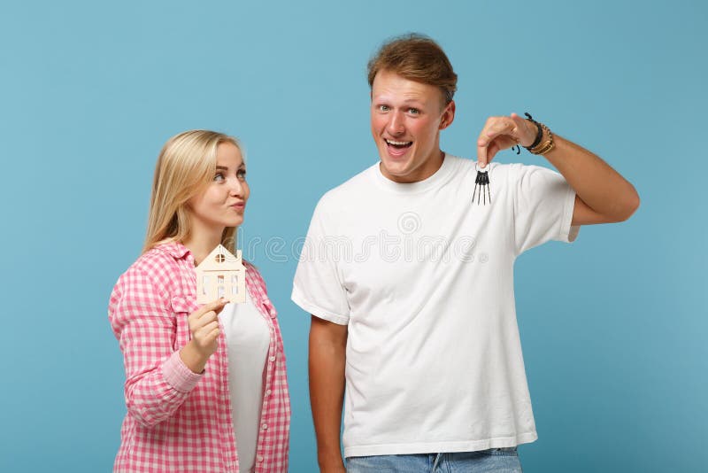 Young joyful couple two friends guy girl in white pink empty blank design t-shirts posing isolated on pastel blue